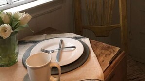 A dining area with a table set for two, a chair, a vase with flowers, and a 'MENU' sign on the wall. - Romantic Refreshing 1890s Cottage Uptown Eureka Springs (Eureka Springs)
