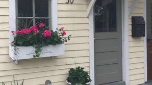 A house with a number 30 on the wall, a window with pink flowers, a statue, and a potted plant on the porch. - Romantic Refreshing 1890s Cottage Uptown Eureka Springs (Eureka Springs)