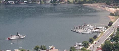 A waterfront area with a large cruise ship docked near a pier, surrounded by residential buildings and greenery.