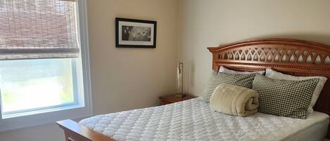 Un dormitorio con una cama de madera, un ventilador de techo, una ventana con persianas y un cuadro enmarcado en la pared.
