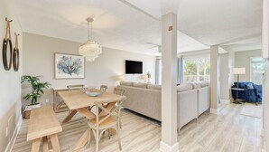 Un salon moderne avec une table à manger en bois, un canapé beige et un lustre.