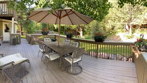 A wooden deck with outdoor furniture, including a table and chairs, and a large umbrella.