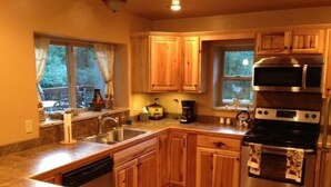 A compact kitchen with wooden cabinets, a stainless steel oven, and a dishwasher.