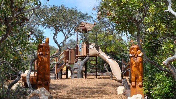 A playground with wooden structures and slides, surrounded by trees and rocks. - Sunglow, Beachfront Deluxe - 2 bed, 2 bath - ocean front unit (Daytona Beach Shores)