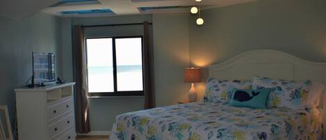Un dormitorio con cama, cómoda, silla, ventana con cortinas y un mural en el techo.