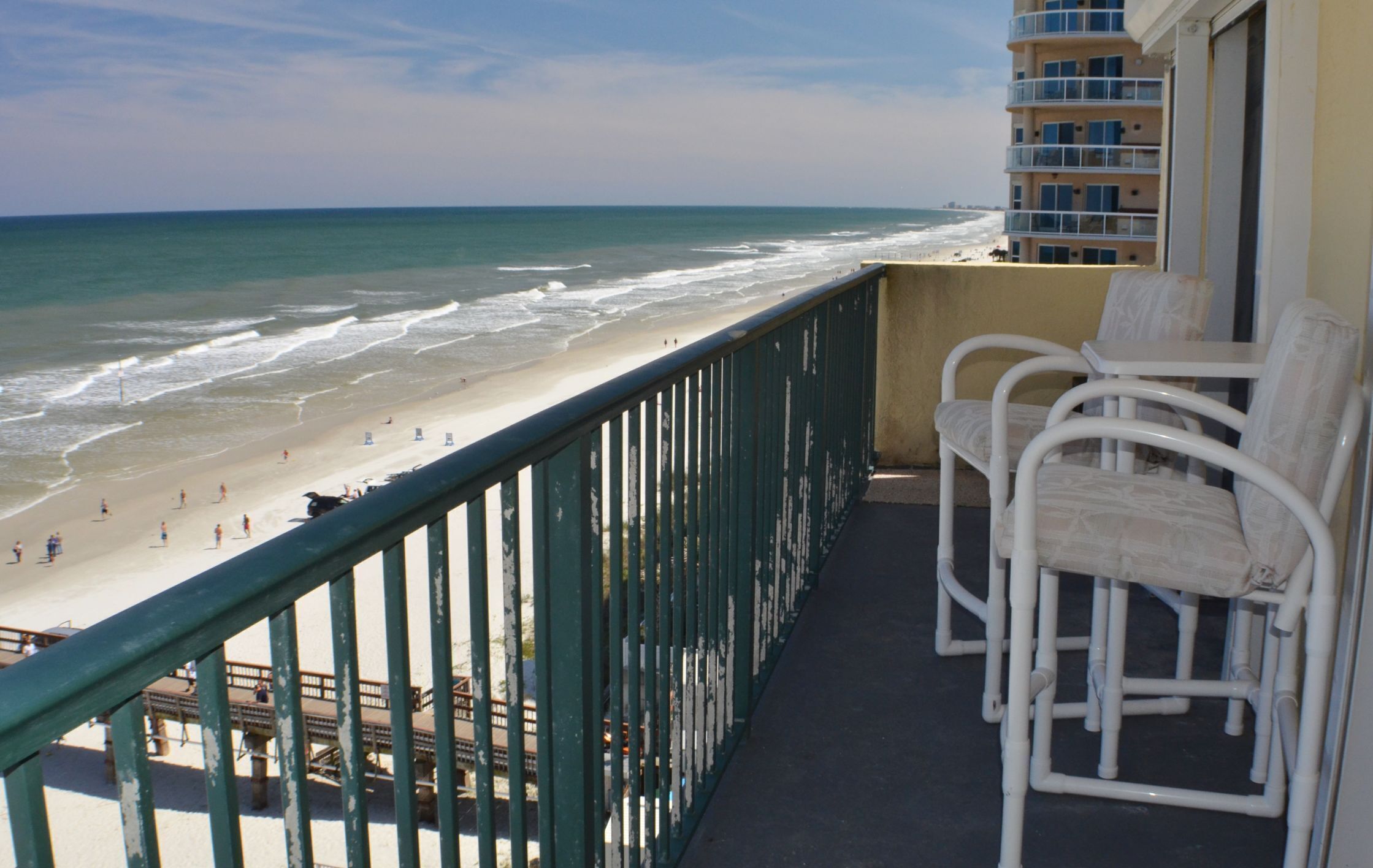 A balcony with a view of the beach and ocean.