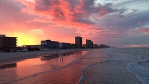 A beach with buildings along the shore, a sunset, and a calm sea. - Sunglow, Beachfront Deluxe - 2 bed, 2 bath - ocean front unit (Daytona Beach Shores)