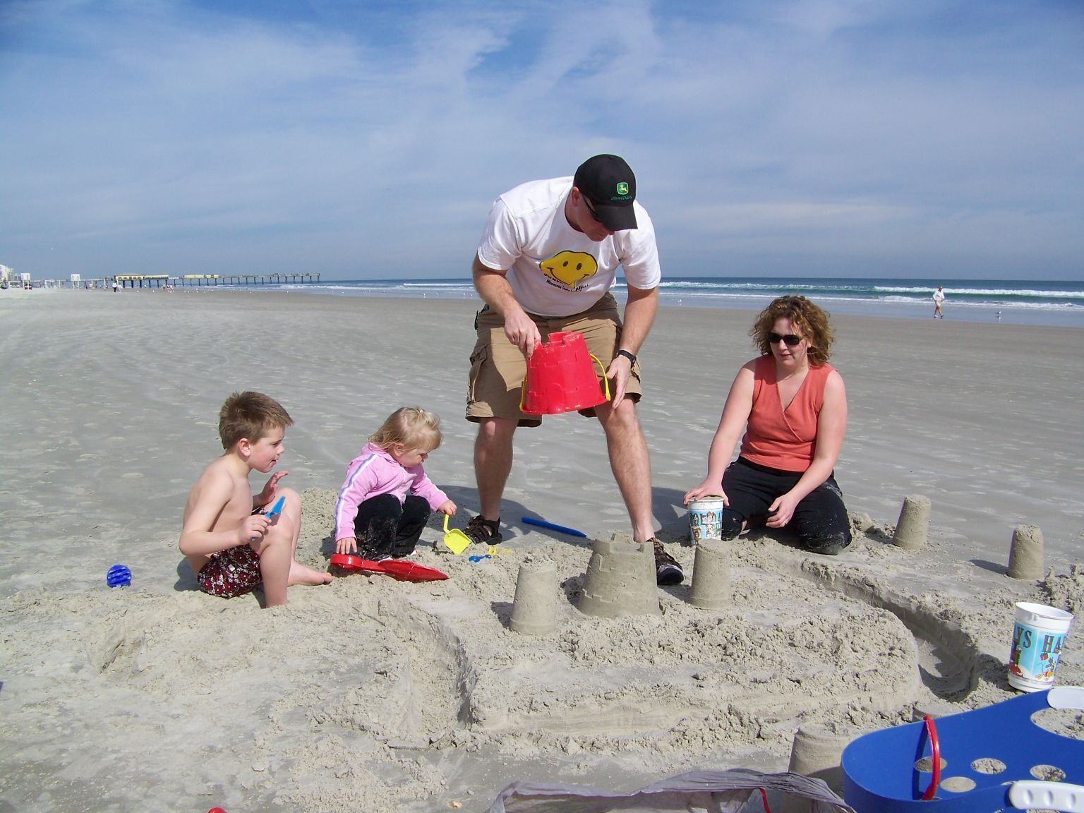 Escena de playa con gente construyendo castillos de arena.