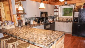 Une cuisine dotée d’un grand îlot central, de tabourets en bois, d’un four à micro-ondes et d’un réfrigérateur.