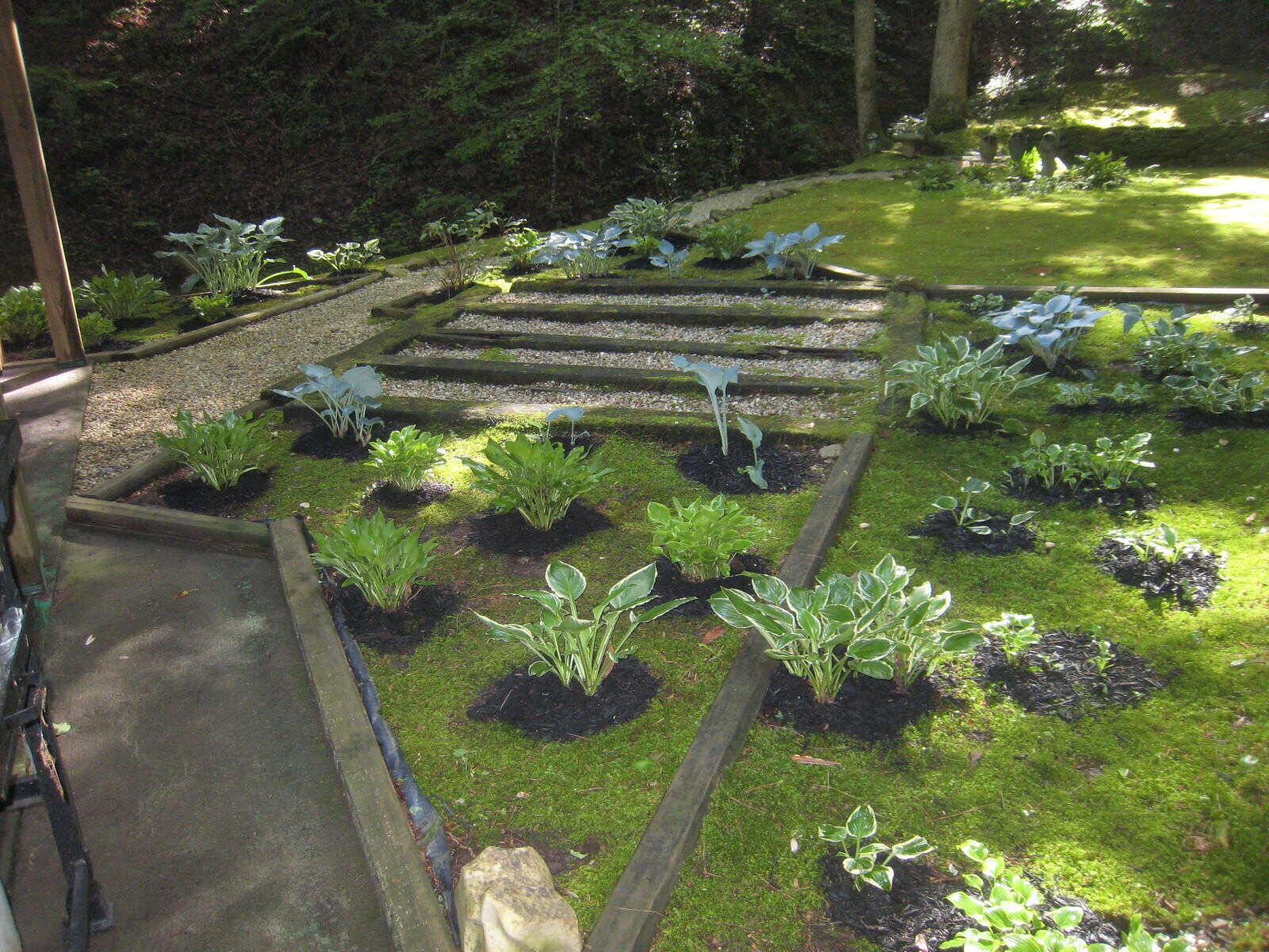 A garden with raised beds and a wooden staircase leading up to a covered area.