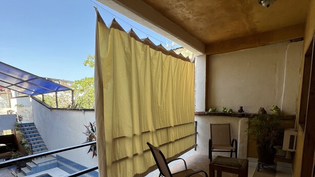 A balcony with a glass pool, a chair, and a table. - Pacefull Condo in Puerto Vallarta  (Lomas del Coapinole)