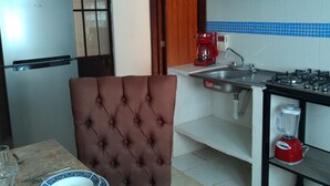 A kitchen with a refrigerator, coffee maker, sink, stove, and a dining area with a chair and table set. - Pacefull Condo in Puerto Vallarta  (Lomas del Coapinole)
