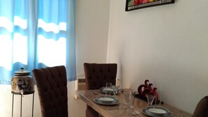 A dining area with a wooden table set for four, surrounded by upholstered chairs. A decorative vase and a fruit bowl are on the table. - Pacefull Condo in Puerto Vallarta  (Lomas del Coapinole)