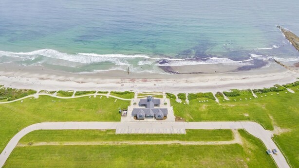An aerial view of a coastal area with a beach, a parking lot, and a building with a dome structure. - 1.5 blocks to Scarborough beach, Narragansett, fenced in yard, AC - New Updates! (Narragansett)