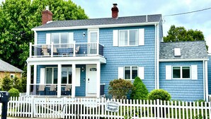 A two-story blue house with a white picket fence, a front porch, and a mailbox. - 1.5 blocks to Scarborough beach, Narragansett, fenced in yard, AC - New Updates! (Narragansett)