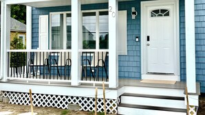 A two-story house with a covered porch, white railings, and a white door. - 1.5 blocks to Scarborough beach, Narragansett, fenced in yard, AC - New Updates! (Narragansett)