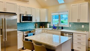 A modern kitchen with white cabinets, stainless steel appliances, a skylight, and a view of the outside. - 1.5 blocks to Scarborough beach, Narragansett, fenced in yard, AC - New Updates! (Narragansett)