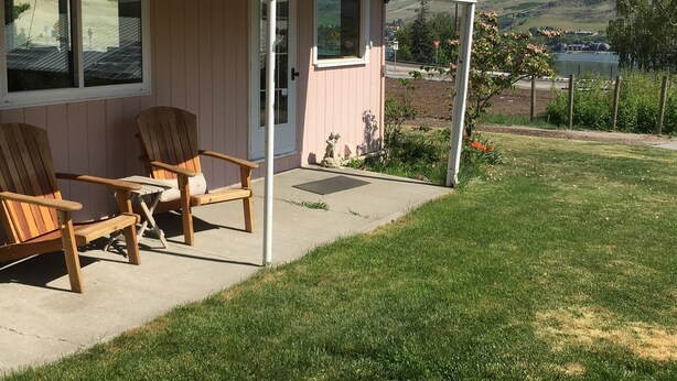 A house with a covered porch, two wooden chairs, and a view of a hilly landscape. - Lake View Home Walking Distance to Town and Vin du Lac Winery (Chelan)