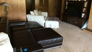 A living room with a brown leather sofa, a white sofa, a bookshelf, and a television. - Lake View Home Walking Distance to Town and Vin du Lac Winery (Chelan)