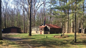 A cabin with a stone exterior, a red roof, and a flagpole. - Little Manistee River Cabin (Irons)