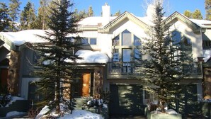 Ein zweistöckiges Haus mit Balkon, umgeben von schneebedeckten Bäumen.