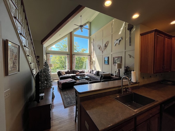 A spacious living area with a large window, a fireplace, and a kitchen with a sink.