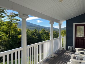 A porch with a view of a mountain and forest.