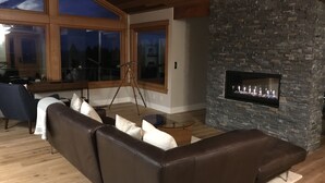 A modern living room with a stone fireplace, leather sofa, and large windows. - Wine country with views (Newberg)