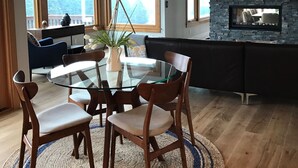 A modern dining area with a glass table, wooden chairs, and a woven rug. - Wine country with views (Newberg)