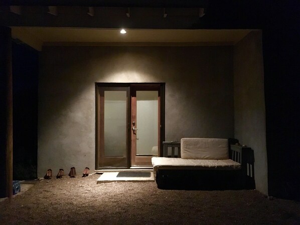 Ein kleiner, schummrig beleuchteter Raum mit einem Einzelbett, einer Schiebetür und Teppichboden.