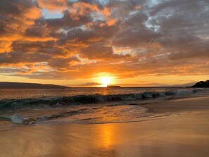 A beach with waves and a sunset.