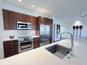 A modern kitchen with built-in appliances, a stainless steel sink, and wooden cabinetry. - Luxury Wailea Villa l Stunning Remodel l 
Couples Retreat l Only 5 Star Reviews (Kihei)