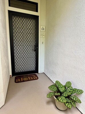 A door with a mesh screen, a doormat with a pineapple design, and a potted plant with variegated leaves. - Luxury Wailea Villa l Stunning Remodel l 
Couples Retreat l Only 5 Star Reviews (Kihei)