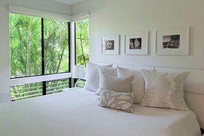 A bedroom with a large bed, a view of greenery through the window, and three framed pictures on the wall. - Luxury Wailea Villa l Stunning Remodel l 
Couples Retreat l Only 5 Star Reviews (Kihei)