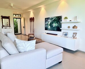 A modern living room with a sofa, a television mounted on the wall, and a white console table with decorative items. - Luxury Wailea Villa l Stunning Remodel l 
Couples Retreat l Only 5 Star Reviews (Kihei)