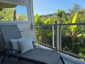 A balcony with a chair and a view of lush greenery. - Luxury Wailea Villa l Stunning Remodel l 
Couples Retreat l Only 5 Star Reviews (Kihei)
