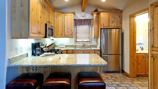 A kitchen with wooden cabinets, a stainless steel refrigerator, a granite countertop, and a window with blinds. - PRL3 by Park City Experience - Ultimate convenience near Deer Valley and Main St (Park City)