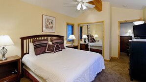 A hotel room with a large bed, two bedside tables with lamps, a ceiling fan, a framed picture on the wall, a mirror, and a television on a stand. - PRL3 by Park City Experience - Ultimate convenience near Deer Valley and Main St (Park City)