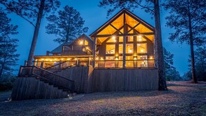 Une cabane en bois dotée d’un grand balcon et de nombreuses fenêtres, entourée d’arbres.