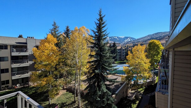 A residential area with a view of a mountain range, a tennis court, and autumn-colored trees. - Luxury Condo w/ FREE WiFi, Parking, Heated Pool, Hot Tubs, Skier Shuttles (Avon)