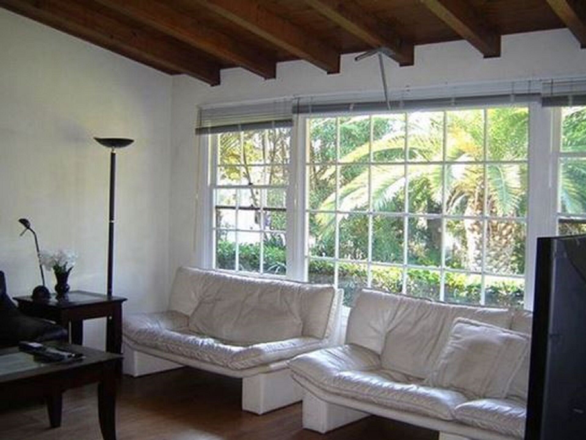 A room with a white sofa, a small table, and a TV.