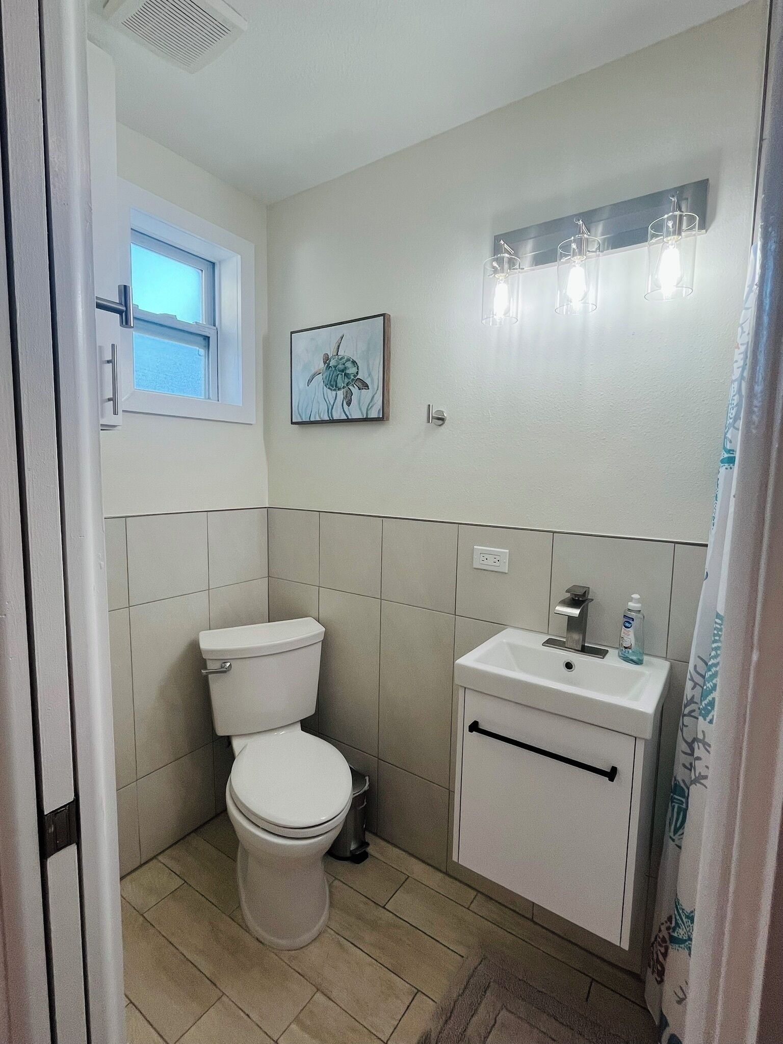 Une petite salle de bain avec des toilettes, un lavabo et une fenêtre.