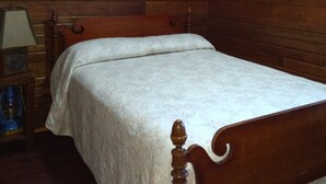 A wooden-paneled room with a bed, a lamp, and a framed picture on the wall. - Cabin #5 On Beautiful Brevort Lake (Moran)