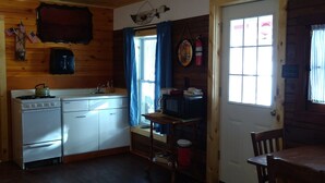 A cabin-style kitchen with wooden walls, a stove, a microwave, and a sink. - Cabin #5 On Beautiful Brevort Lake (Moran)