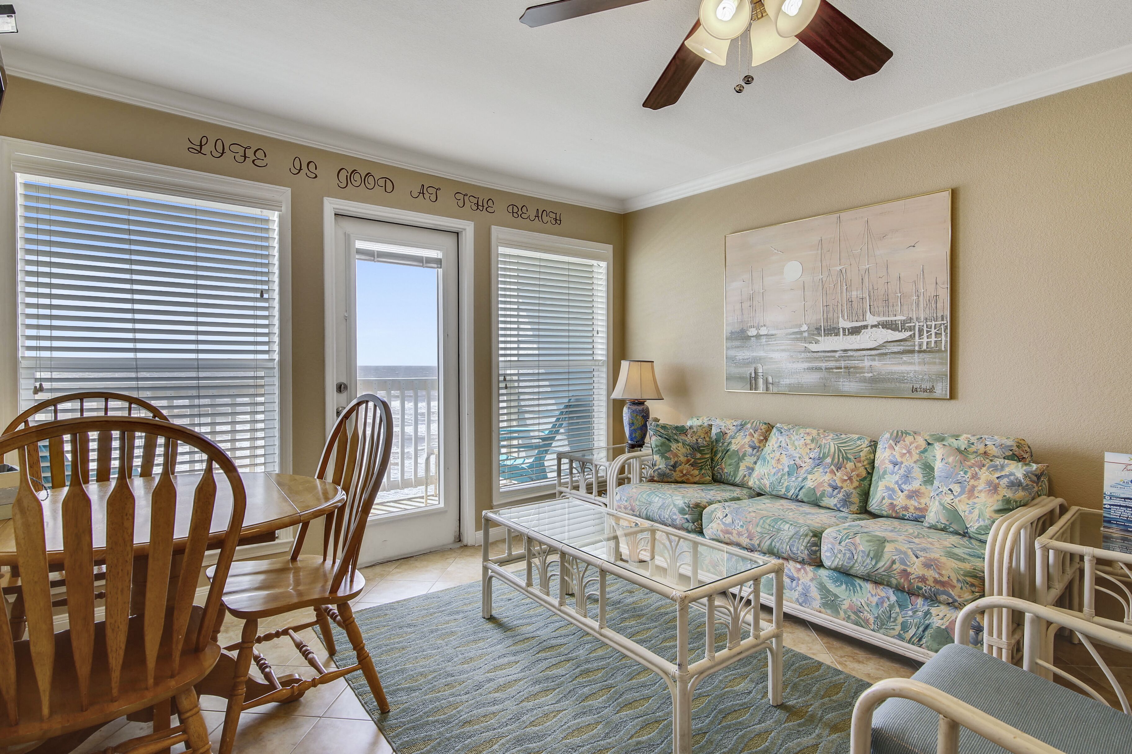 A living room with a dining table, chairs, a sofa, and a ceiling fan.