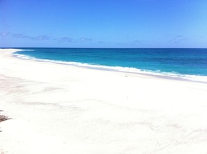 A beach with white sand and clear blue water.