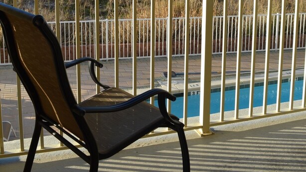 Une vue sur la plage depuis un balcon, avec une chaise, une piscine et une clôture.