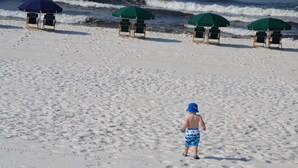 Une plage où l’on voit des empreintes de pas menant à un poste de surveillance des sauveteurs.