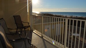 Un balcon avec vue sur l’océan, une balustrade blanche et deux chaises.