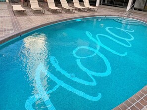 Una piscina con bordo piastrellato e motivo blu sulla superficie dell'acqua.